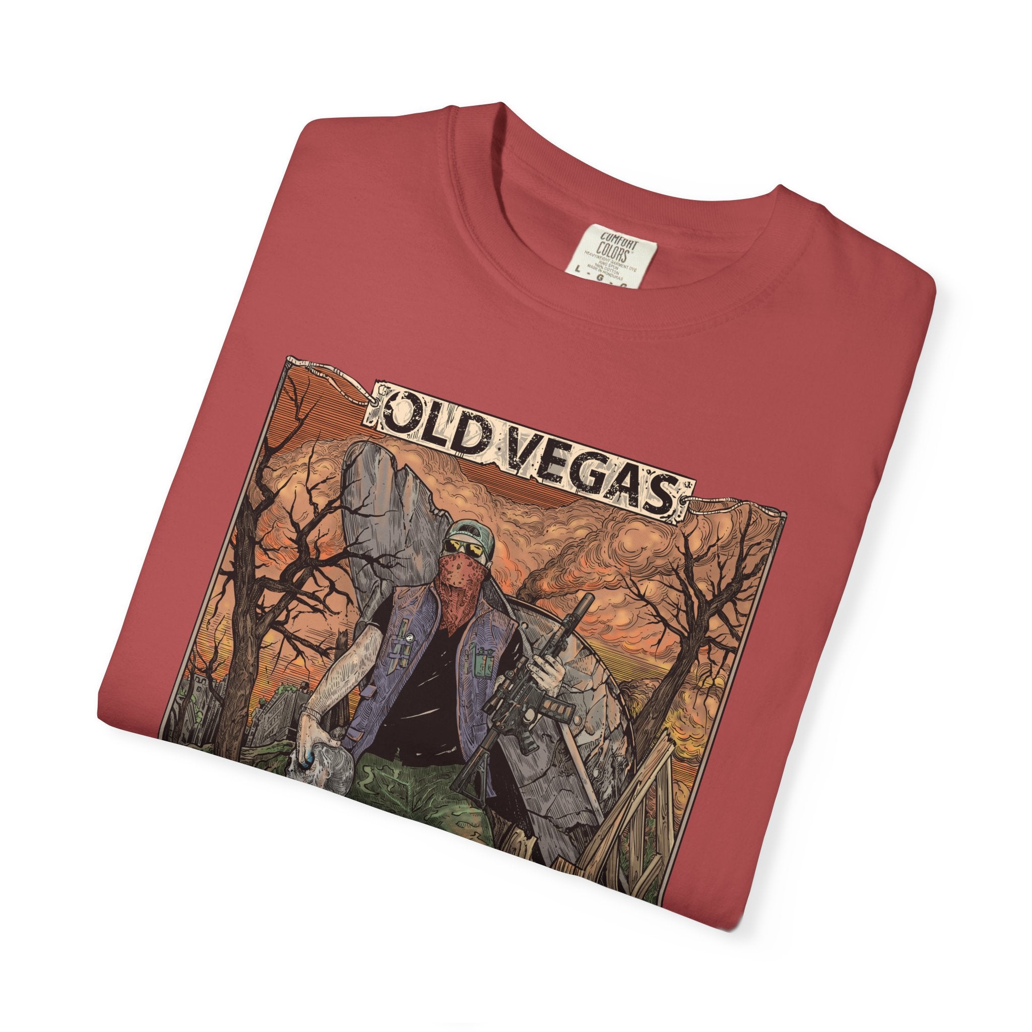 A folded red cotton graphic tee featuring an old vegas themed rugged figure in warm orange and brown tones