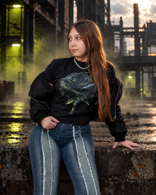 Model wearing the OLD VEGAS Apocalyptic Rose black graphic tee with a gray and lime-green rose print and open black jacket.