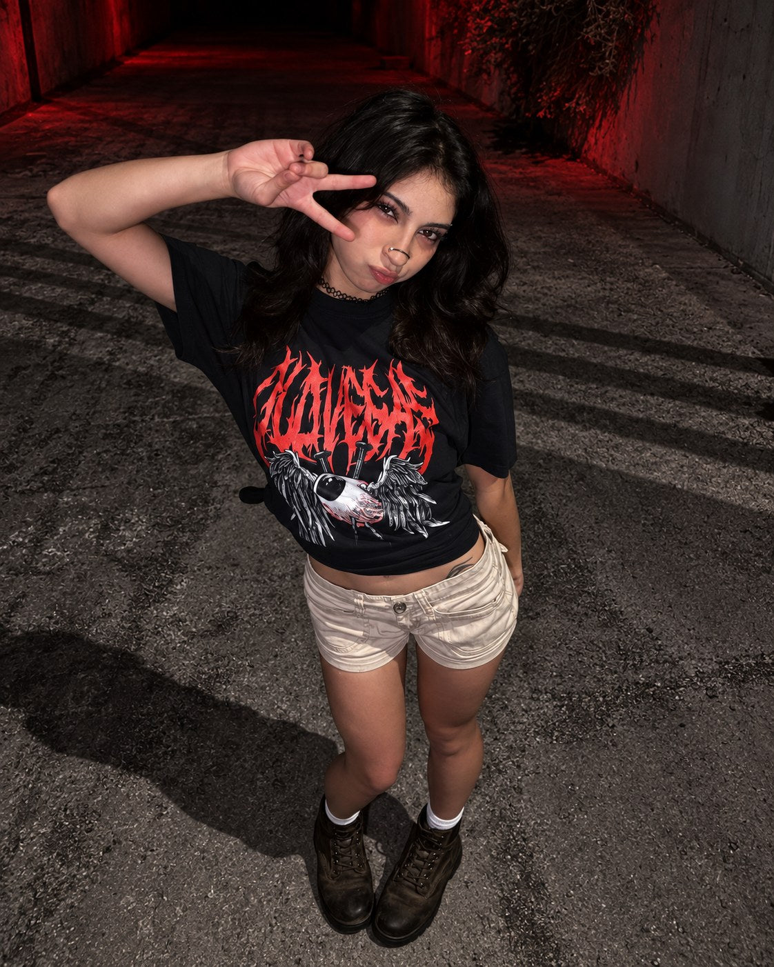 High-angle view of a model making a peace sign in the OLD VEGAS Dead Eyes black graphic tee.